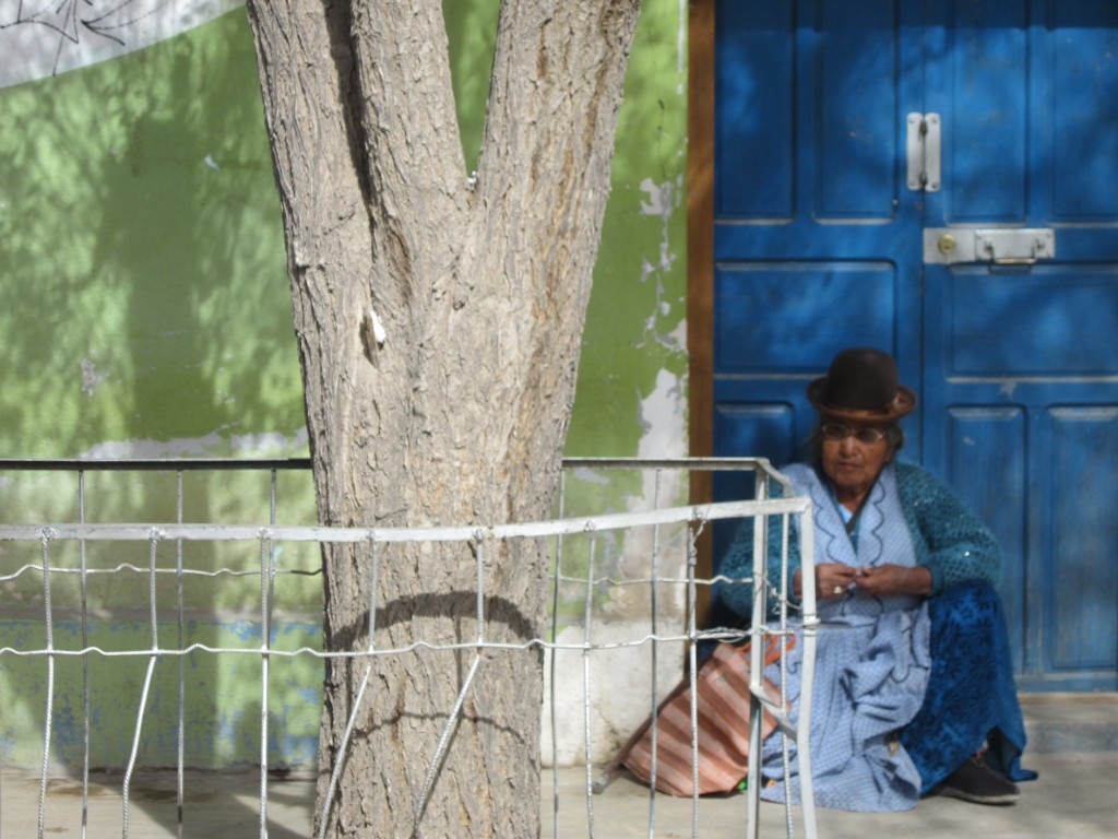 A woman sits on a doorstep in Uyuni