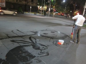 A street artist with a mop and a bucket of water