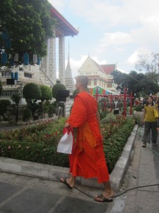 A Buddhist monk rushes by wearing his orange robes
