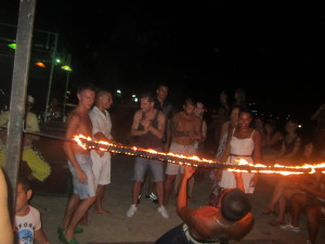 One of the professionals limbo dances really low under the lit rope!