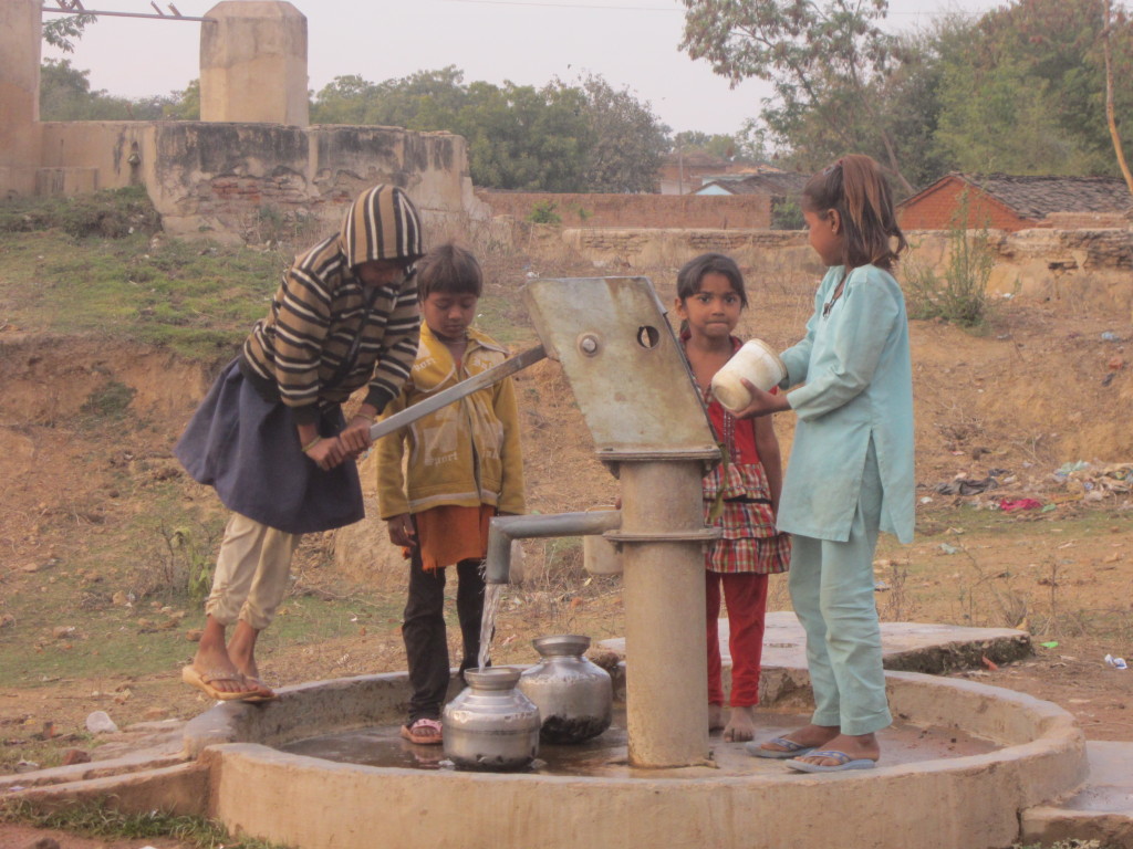 Children fill waterpots at the village well