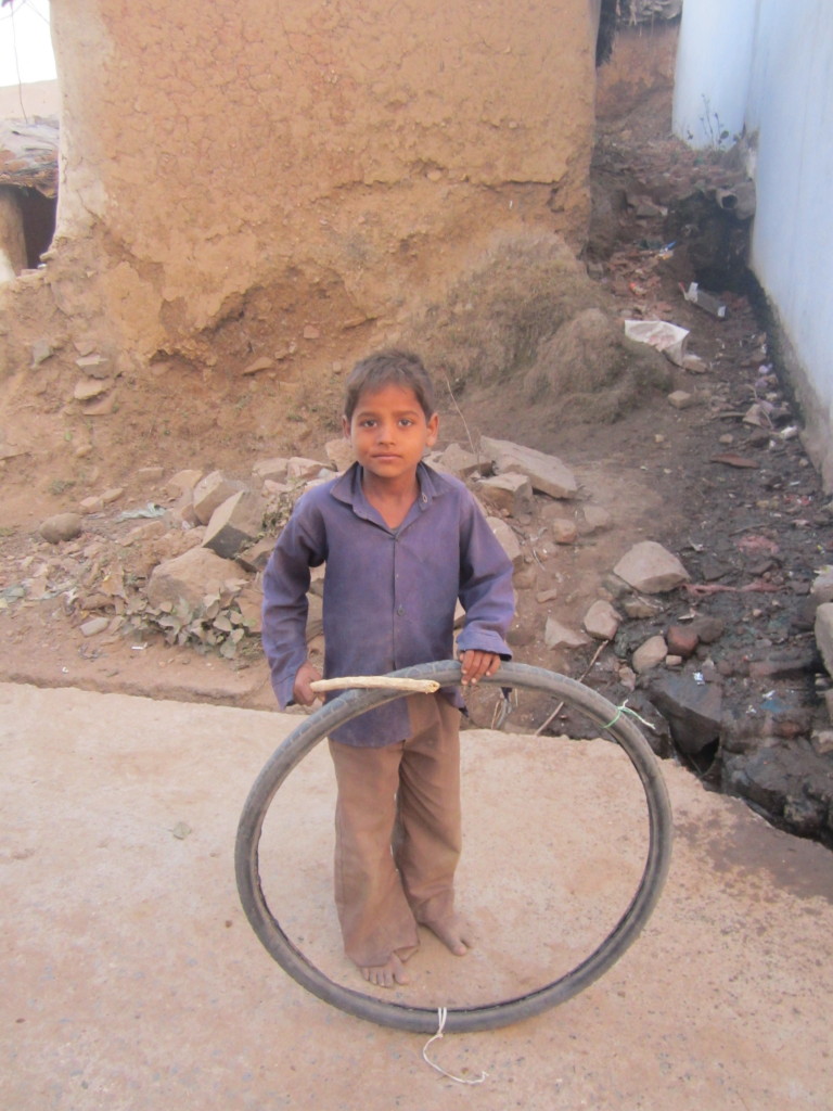 A boy plays with a tyre-inner and stick