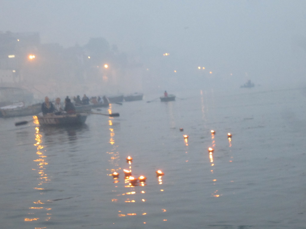 The candles and flowers float peacefully down the Ganga
